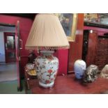A large table lamp with floral decoration and a silk pleated shade and beaded fringe,