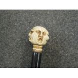 A walking stick with carved animated face knop