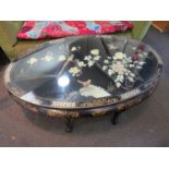A 20th Century oriental lacuered oval coffee table with mother of pearl and gilt border,