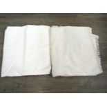 Two white cotton bedspreads with a raised stitched pattern, one with fringing and stain to one area,