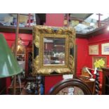 An ornate black and gilt framed bevel edged mirror,