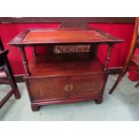 A Chinese style mahogany two tier cabinet/occasional table the dished top on turned supports over a