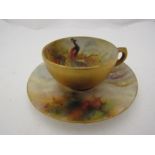 A Royal Worcester porcelain miniature cabinet cup and a similar saucer painted with a peacock and