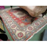 A red, cream and blue ground tasselled end rug with Aztec detailing,