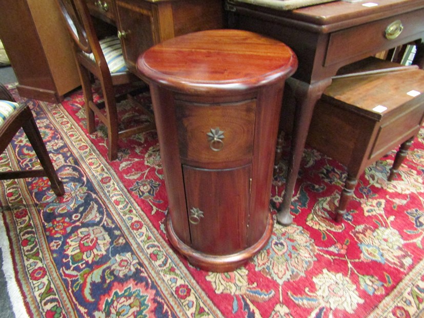 An Eastern hardwood cylindrical bedside chest with single drawer over a single door,