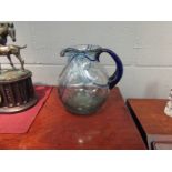 An art glass water jug with blue swirl design