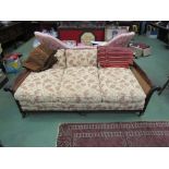 A late Victorian mahogany three seater bergère sofa with carved acanthus leaf decoration on turned