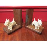 A pair of oak book ends mounted with painted metal terriers