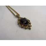 A 9ct gold pendant set with a dark orange stone hung on a 9ct gold chain, 46cm long, 5.