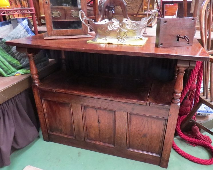 An 18th Century revival oak Monks bench the drop down table top over a hinged seat box seat settle