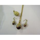 An enamel egg pendant hung on chain with a pair of matching earrings and egg pendant