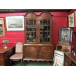 An 18th Century style walnut double dome top two door panel glazed bookcase on two door base and