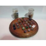 A Victorian mahogany solitaire board and glass marbles,