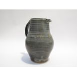 A leach pottery St Ives jug, tenmoku and slip glaze, incised title 'One and All' filled with glaze.