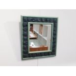 RON HITCHINS (1926-2019): A wall mirror with 30 ceramic tiles set in the frame with a slate blue
