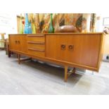 A Mid 20th Century long teak sidecabinet, three drawers with flanking pull and slide doors. 212.