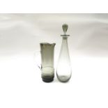 A Holmgaard smoked glass decanter and stopper and jug of cylindrical form and moulded ribbing.