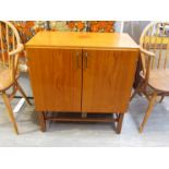 A teak small cabinet with twin cupboard doors, shelved interior,raised on square legs. 68.