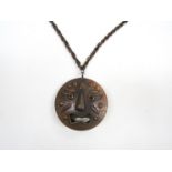 A bronzed modernist style metal two faced pendant, one side happy, the other side sad.
