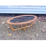 A mid 20th Century eliptical coffee table with glass inset top.