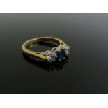 An 18ct gold diamond and sapphire ring the central oval sapphire flanked by brilliant cut diamonds,