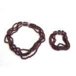 A four strand garnet bead necklace with cabochon garnet and white sapphire clasp,