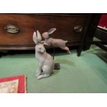 A wooden sculpture of a hare on stand together with a resin hare sculpture