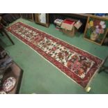 A wool runner rug, floral sprays, red border, tasselled fringe, 2'4 x 11'6,