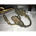 A pair of antique brass curtain tie backs with floral brass work.