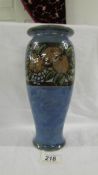 A Royal Doulton 27 cm high mottled blue vase with a band of grapes and another fruit near the top.