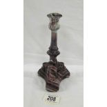 A Victorian pressed purple candlestick on three feet, each with the face of some creature,