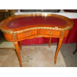 A kidney shaped ormolu mounted writing desk with leather inset top.