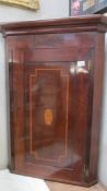 A mahogany inlaid corner cupboard.