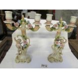 A pair of early 20th century porcelain candlestick surmounted cherubs and with lift off tops.