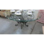 A contemporary circular coffee table on wrought iron base with glass top.