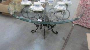 A contemporary circular coffee table on wrought iron base with glass top.