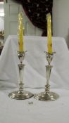 A pair of 24 cm tall silver candlesticks on oval stepped bases.