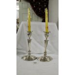 A pair of 24 cm tall silver candlesticks on oval stepped bases.