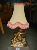 A gilded table lamp surmounted cherub on alabaster base.
