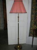 A brass standard lamp with shade.