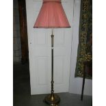 A brass standard lamp with shade.