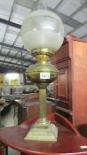 A brass oil lamp with shade and chimney.