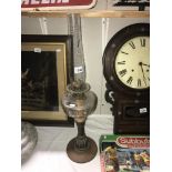 An oil lamp with copper and brass stand, a faceted font and chimney but no shade.