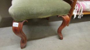 An Edwardian mahogany framed footstool with green dralon upholstery.