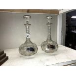 A pair of cut glass decanters with silver plate labels.