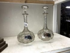 A pair of cut glass decanters with silver plate labels.