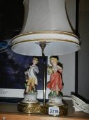 A good double porcelain figure table lamp on brass base, in good condition.