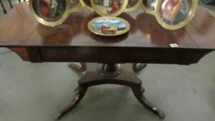 A good quality mahogany table with dropsides and on brass lion paw feet.