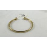A 9ct gold bangle, 9.5 grams. (small dint).