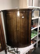 A Victorian bow front oak corner cupboard with banded inlay.